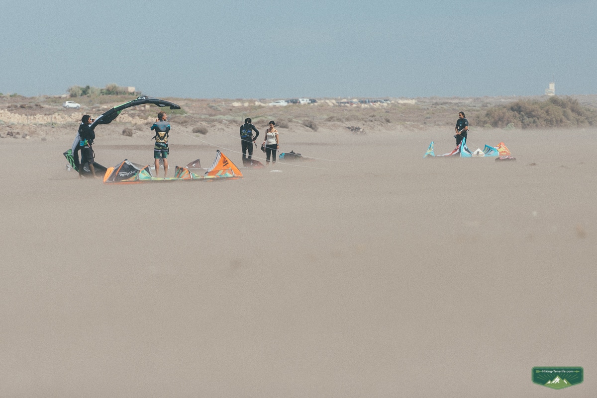Kitesurfers preparing in wind-blown sand at La Tejita