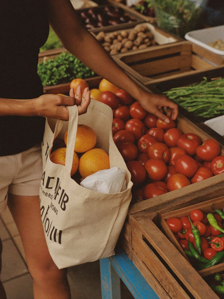 A shopper placing market produce into a cloth bag