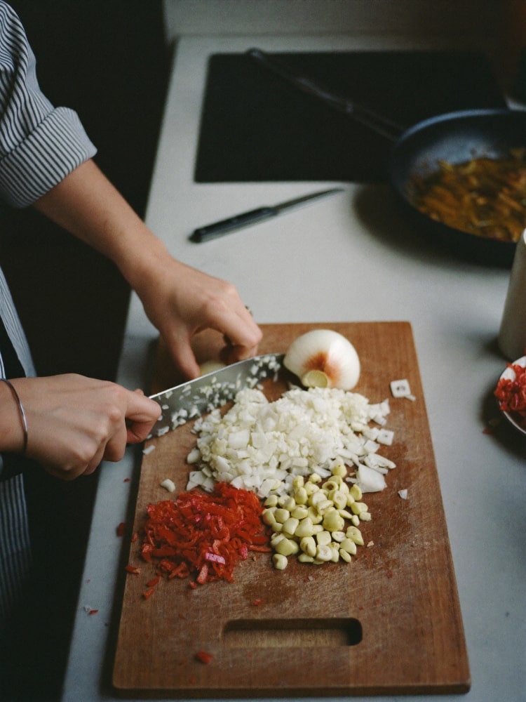 Hands chopping vegetables on a kitchen board
