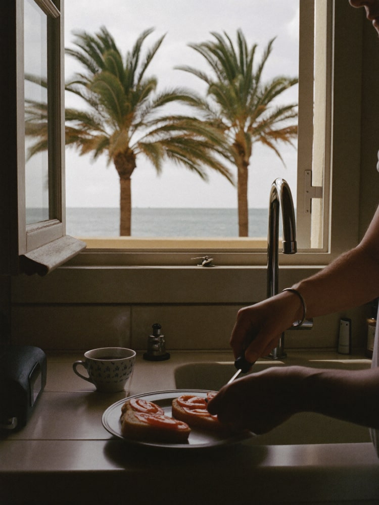 Drinks beside a window overlooking a palm tree and the sea