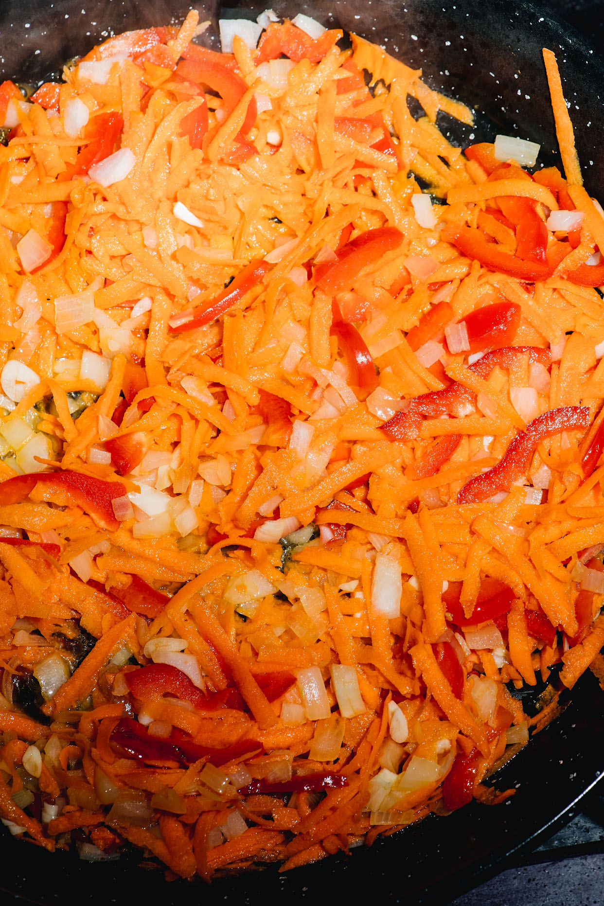Onion carrot and red pepper cooking in a pan for paella sofrito