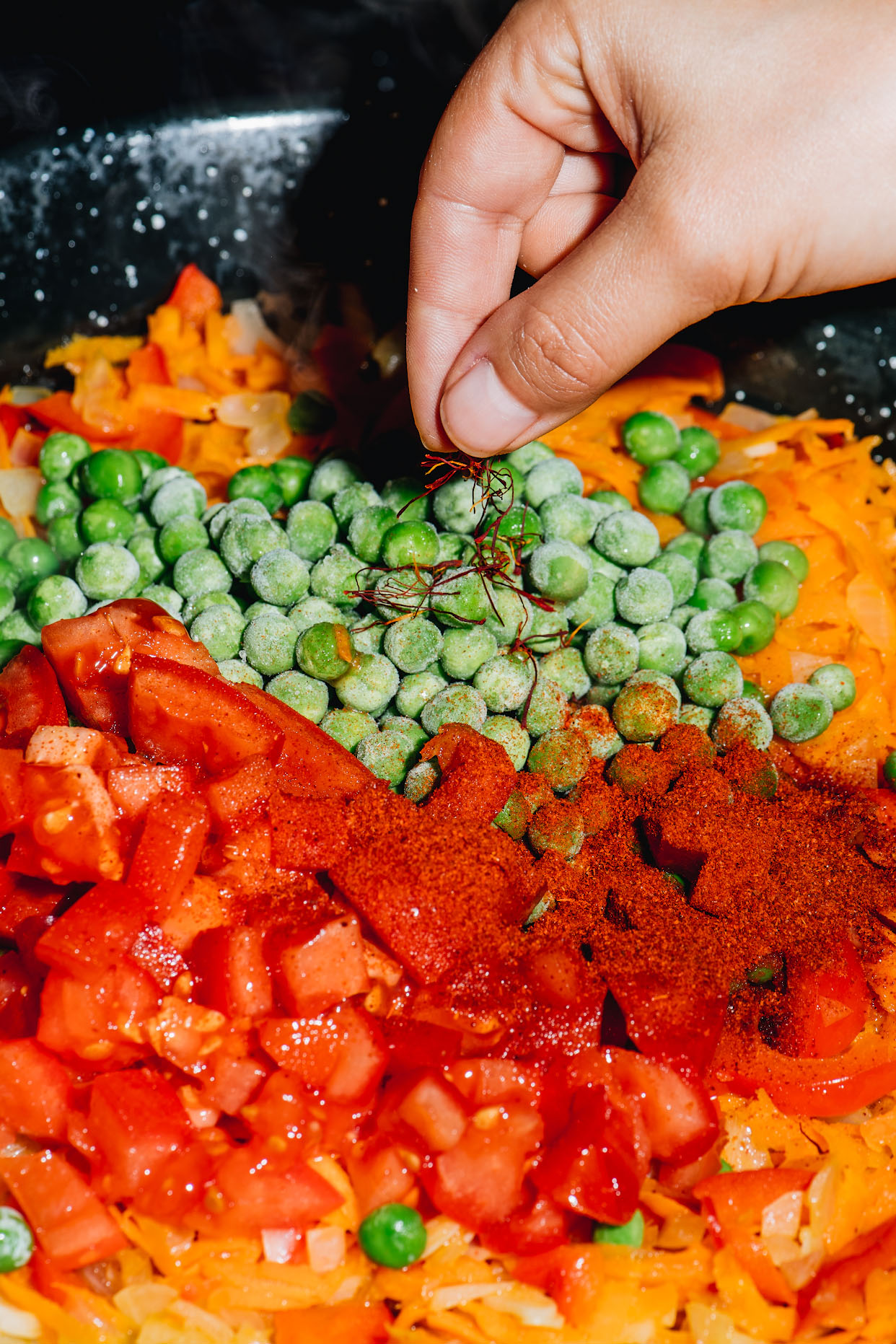 Saffron paprika tomatoes and peas added to seafood paella vegetables