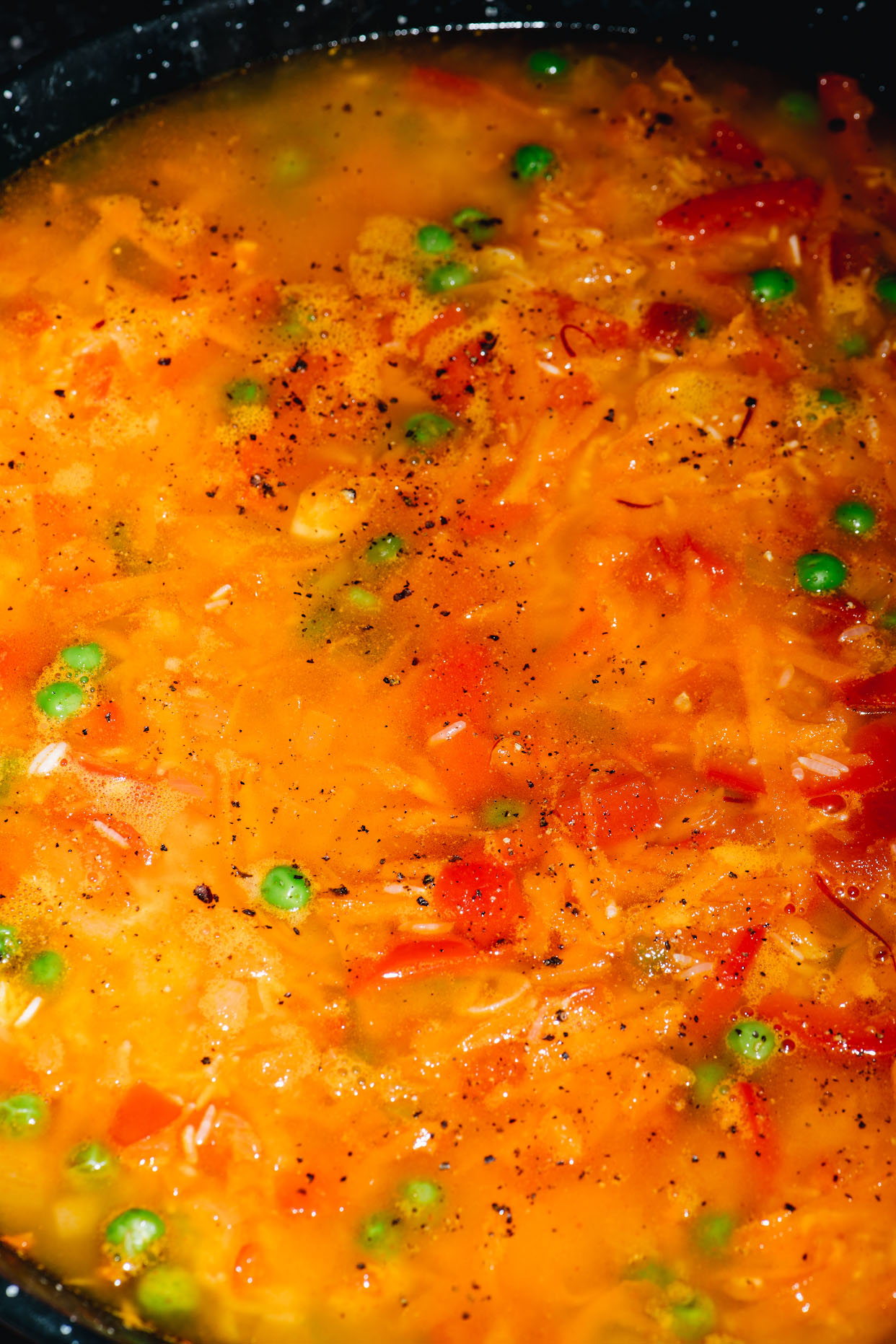 Seafood paella stock simmering with rice peas and vegetables