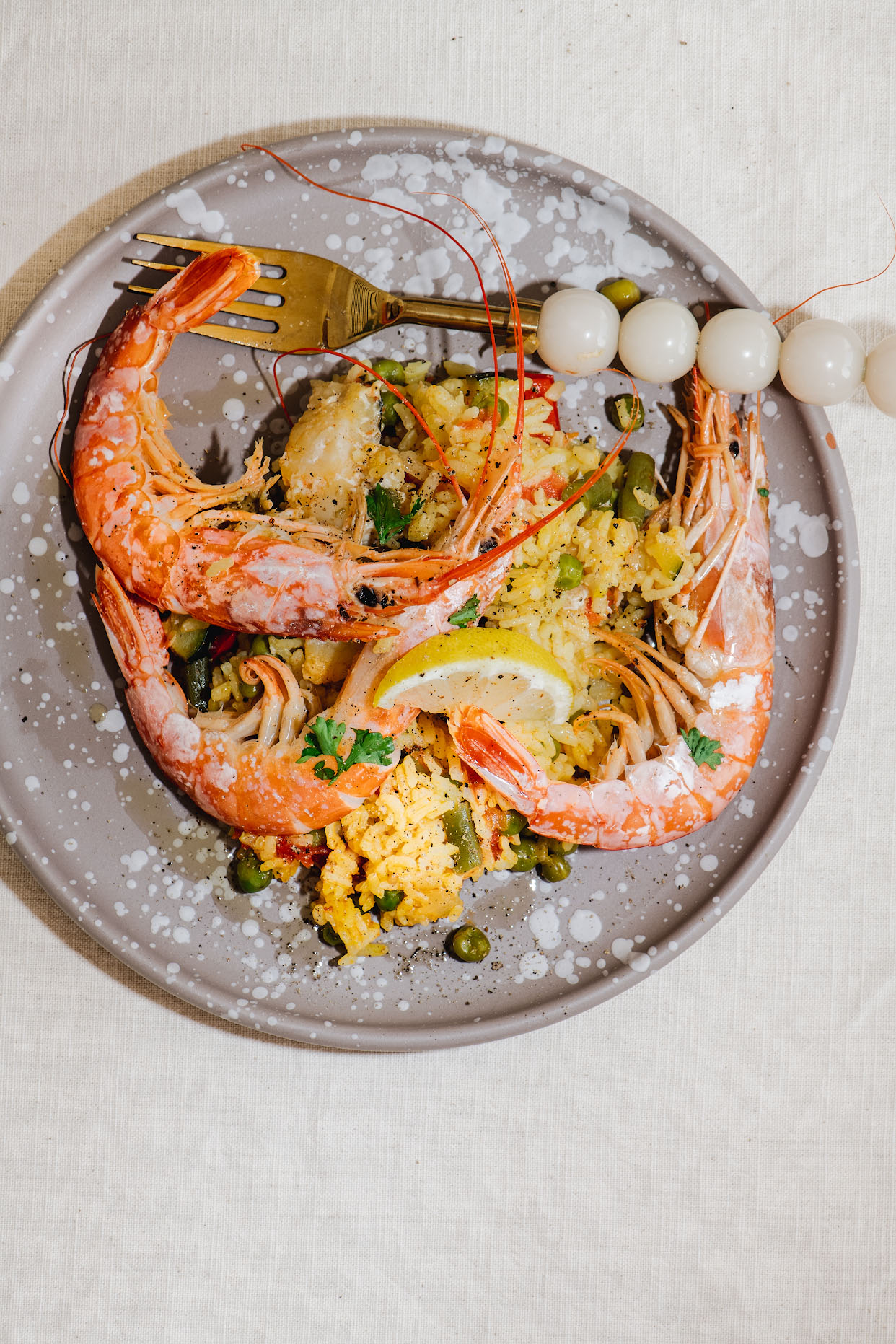 Plated seafood paella with two whole prawns lemon and parsley