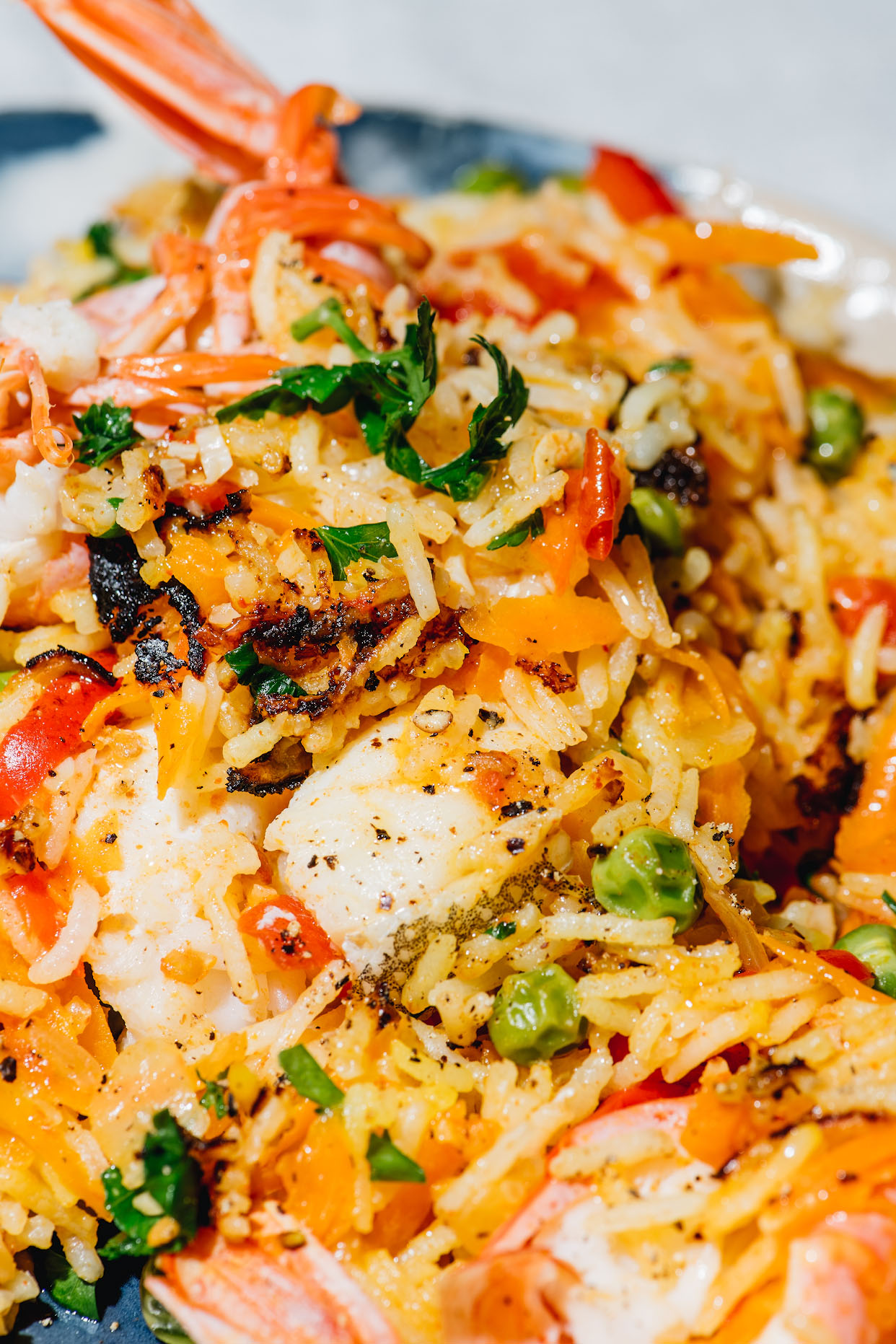 Close-up of seafood paella rice with white fish prawns peppers and peas
