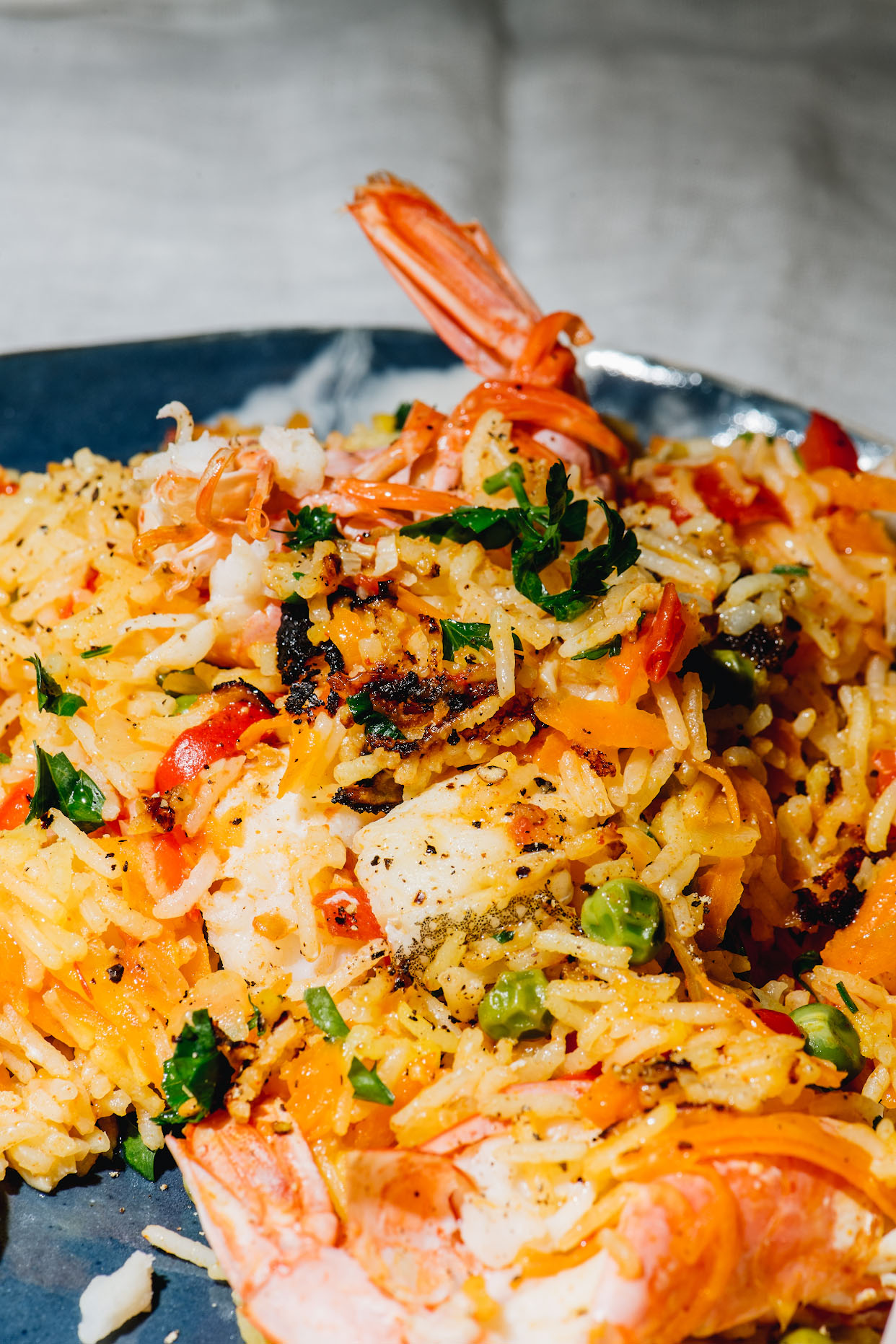 Close-up of seafood paella with grilled white fish peppers peas and prawns